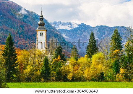 Gorgeous view of colorful autumnal scene of famous Church of St John the Baptist at Bohinj Lake. In the background the Vogel mountain. Ribicev Laz, touristic village in Slovenia