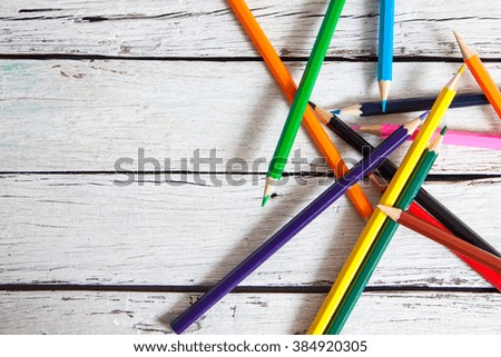 Stack of colored pencils in a glass on wooden background