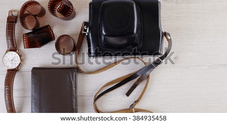 Work space for photographer, designer or hipster style. Have a film camera, film, watch, wallet, knife on wooden table.