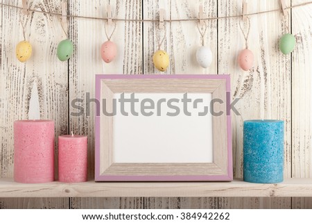 Easter eggs on clothespins, candles and blank wooden frame