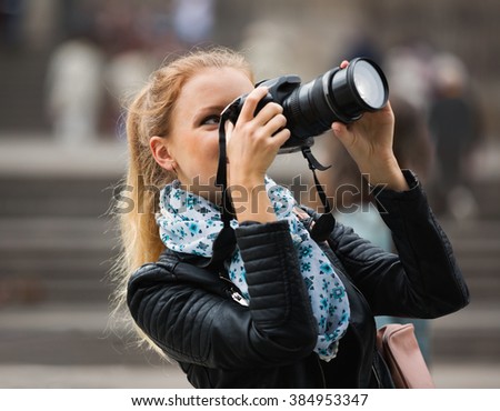 Europenian joyful girl taking pictures of sights at city excursion