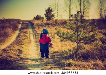 Vintage photo of young happy boy playing outdoor in beautiful rural landscape in golden light at spring. Happy childhood spent in the countryside.