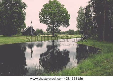 country house with pond and oak trees in green summertime - vintage effect
