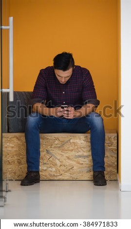 young man in crative box working on smart phone, startup business modern office room  interior