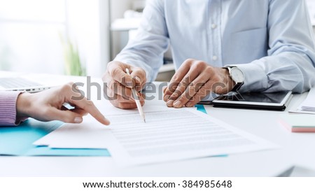 Business people negotiating a contract, they are pointing on a document and discussing together Royalty-Free Stock Photo #384985648