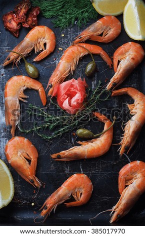 Fresh shrimp in the shell with a lemon, spices and herbs on a dark background