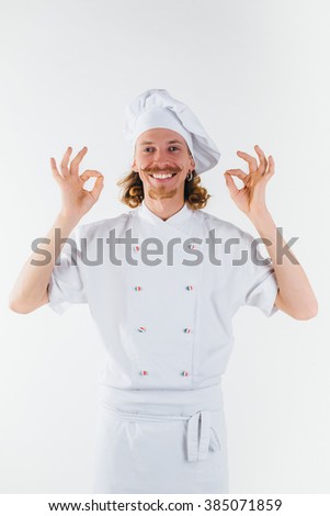 Chef with long red hair in white uniform shows ok sign and smile. Cooking the meal. Vertical portrait of chef
