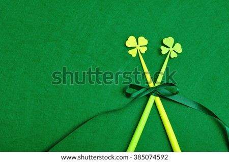 A four leaf clovers on a sticks tied together with a green bow isolated on a green background for St. Patrick's day