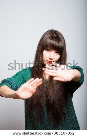 long-haired girl shows gesture stop, student isolated on a gray background