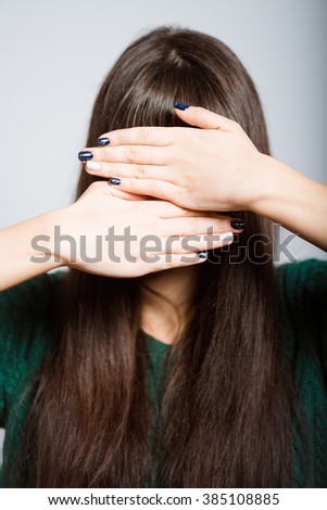long-haired girl hides her face in her hands, a student in isolation on a gray background