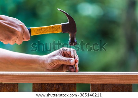 Using hammer and nail on wood and bokeh background Royalty-Free Stock Photo #385140211