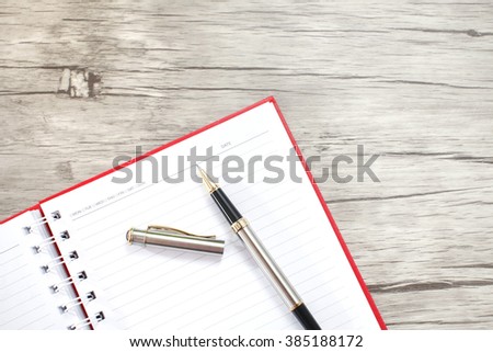 Notebook with fountain pen on wooden table 