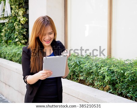 Excited businesswoman using digital tablet computer on the street