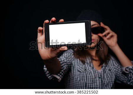 Hipster cool girl taking picture on smartphone self-portrait, screen view, snapshot studio on a black background, Phone white screen