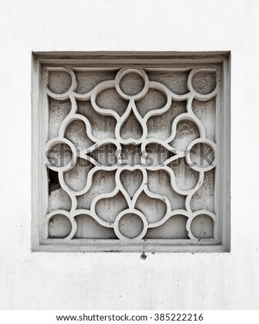 A vintage stone mason window frame with exotic symbol and pattern.
