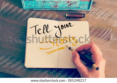 Retro effect and toned image of a woman hand writing a note with a fountain pen on a notebook. Handwritten text Tell Your Story as business concept image Royalty-Free Stock Photo #385248217