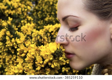 Young beautiful smiling woman smells yellow florets in spring. Close up portrait