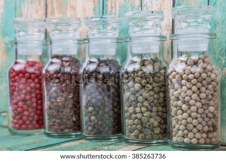 Various kind of peppercorns in glass vial over wooden background