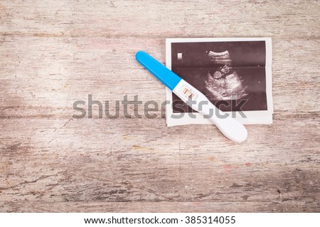 ultrasound with pregnancy test on wooden background Royalty-Free Stock Photo #385314055
