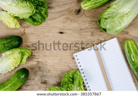 baby cos and cucumber with white blank notebook on old wood desk