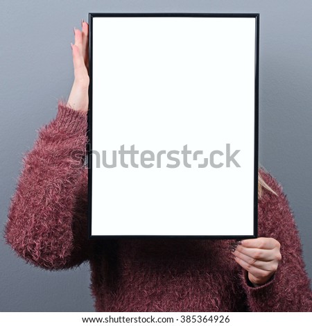 Portrait of woman hiding behind blank sign board