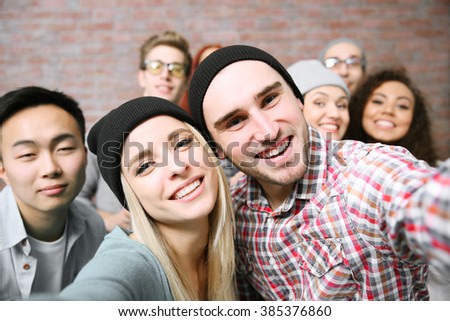 Young people taking group photo on brick wall background