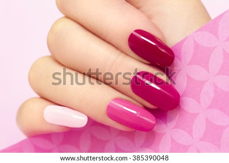 Multicolored manicure with different shades of pink nail Polish on women's hand. Royalty-Free Stock Photo #385390048