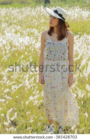 A happy girl at meadow in the early morning. Sun shine with golden light, silhouette back light on her body and grass flowers. Image create for people, healthcare, fashion and cosmetic.