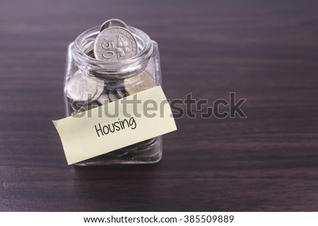Financial concept. Money in the glass on wooden table with Housing word and copy space area.