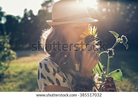 Girl smells sunflower in nature Royalty-Free Stock Photo #385517032