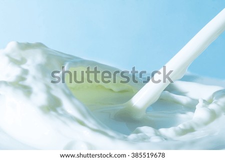 splash of milk, pouring jet stream of milk on a light blue background