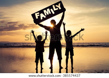 Happy family standing on the beach at the sunset time. Parents hold in the hands  inscription "Family". Concept of happy family.