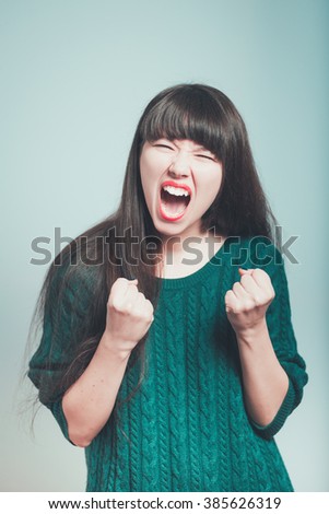 Portrait of a young woman rejoices victory, isolated on a gray background