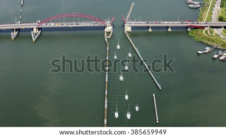 Aerial view of an opened bridge, the SCHELLINWOUDERBRUG in Amsterdam Schellingwoude, Holland. There is a traffic jam from cars on the bridge. Nine sailboats are just passing the bridge.