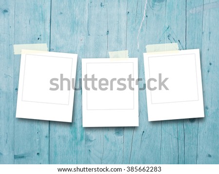 Close-up of three square photo frames with adhesive tape on aqua wooden boards background