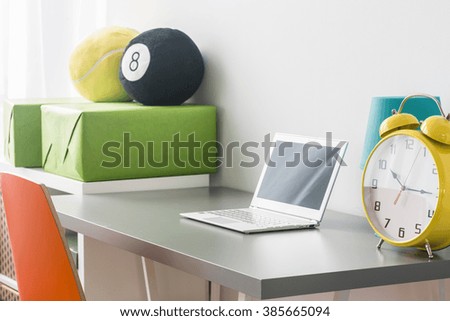 Cropped picture of a desk with a laptop and a huge alarm clock on it