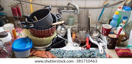 Pile of dirty utensils in a kitchen washbasin Royalty-Free Stock Photo #385710463