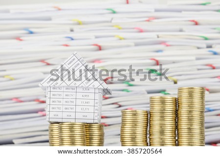 House on pile of gold coins with step pile of gold coins have blur overload of confused paperwork with colorful paperclip as background. Business and finance concepts rich and successful photography.