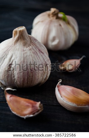 Whole heads of fresh garlic and a few cloves on dark wooden surface