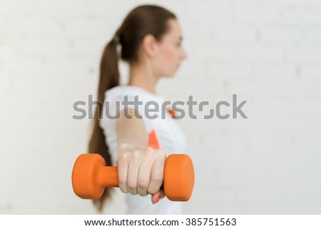 Young woman doing exercises with dumbbells in the gym.