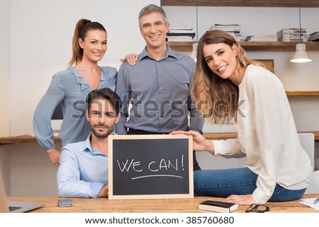 Proud businesspeople in office showing We Can blackboard. Leader with his colleagues posing in office. Group of businesspeople holding their statement at office. 
