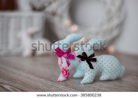 Handmade textile easter bunnies on a white wooden background in a light interior