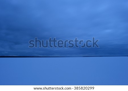 The sky over the lake in winter in dense clouds late in the evening before snow precipitation
