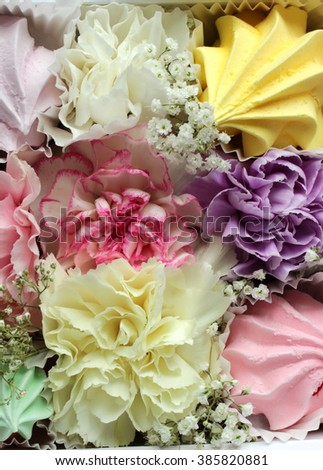 Floral background with pastry and carnations: white, pink, violet, yellow color; spring theme