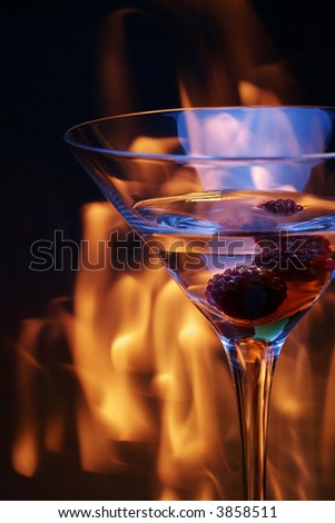 cocktail glass with raspberries over fire traces
