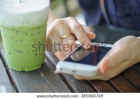 asian girl using smart phone with iced greentea