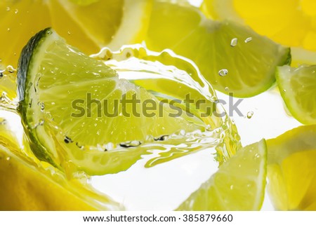 Water splash with yellow lemon and green lime.