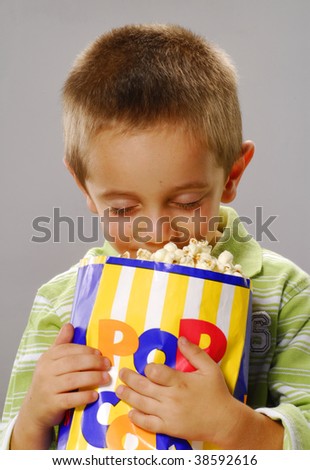 One little boy holding a popcorn bag.boy holding a popcorn bag.  Boy eating popcorn.