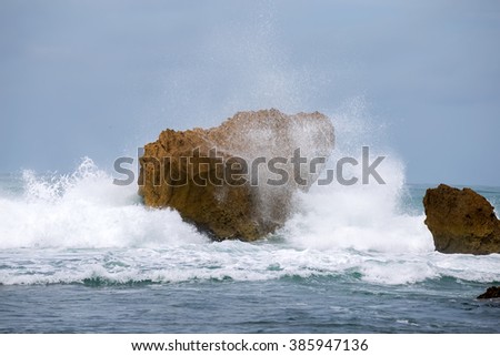 Ocean water waves breaks over rocks Yogjakarta, Indonesia.Image contain noise, blur due to slow shutter speed.