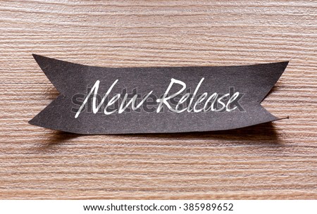 New Release words written on Black papper with wooden background